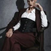 Serre-taille noir brodé porté avec veste bordeaux et chemise blanche, mannequin assise