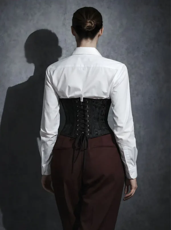 Serre-taille noir brodé, vue de dos, laçage ajustable sur chemise blanche