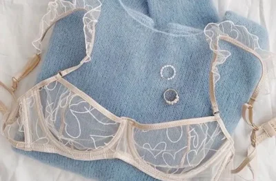 soutien gorge rose clair sur pull col roulé bleu plié avec bijou