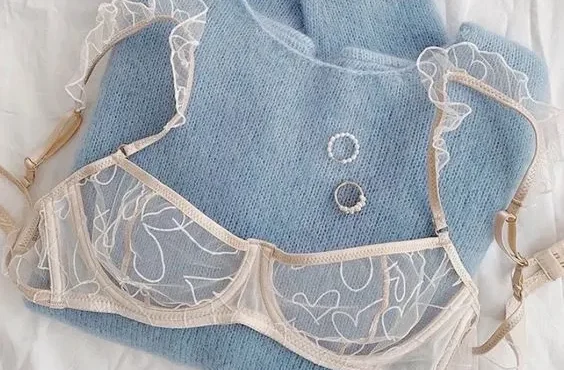 soutien gorge rose clair sur pull col roulé bleu plié avec bijou