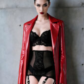 Porte-jarretelles rétro Sombre Secret noir porté sous manteau cuir rouge ouvert, fond béton