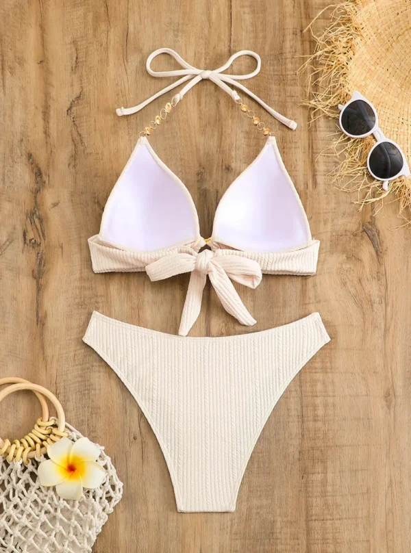 bikini-blanc-texture-dos Bikini blanc texturé côtelé, vue de dos montrant les bretelles nouées et les chaînettes dorées.
