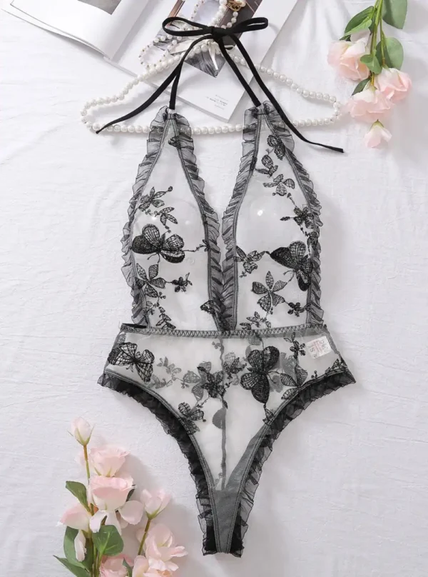 Body transparent dos nu avec broderies noires présenté à plat, détails visibles du tulle et des motifs floraux.