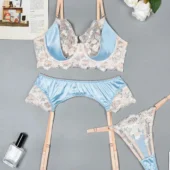 Lingerie satin bleu ciel et dentelle fleurie présentée à plat — soutien-gorge, string et porte-jarretelles