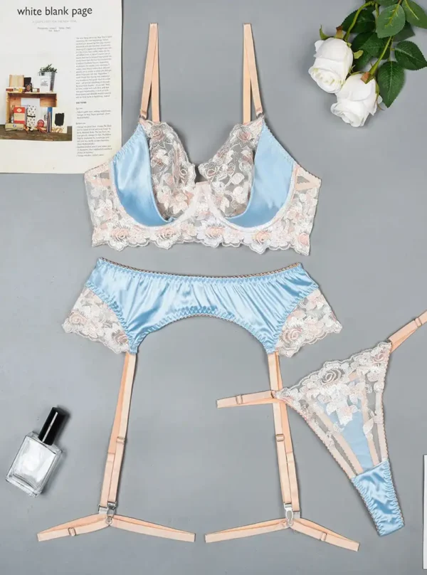 Lingerie satin bleu ciel et dentelle fleurie présentée à plat — soutien-gorge, string et porte-jarretelles