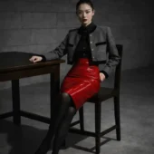 Jupe moulante cuir Fatal Flow rouge, pose assise sur chaise bois, veste grise et table sombre
