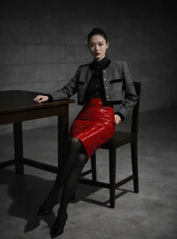 Jupe moulante cuir Fatal Flow rouge, pose assise sur chaise bois, veste grise et table sombre