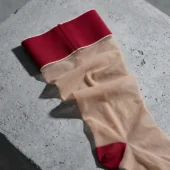 Bas autofixants Ligne de Conduite rouge sang posés à plat sur béton, détail pointe et bande